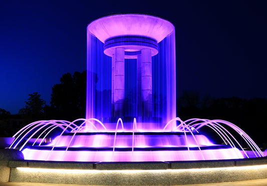 A water fountain lit up with purple lights