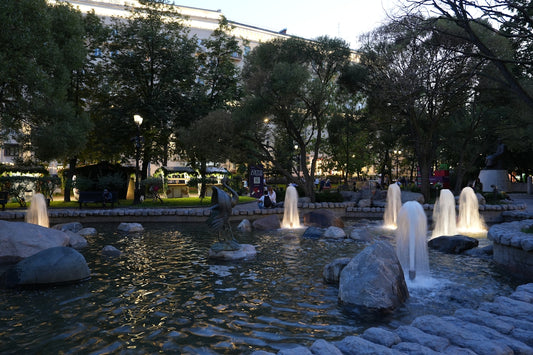 Fountains are illuminated in a tranquil park setting.