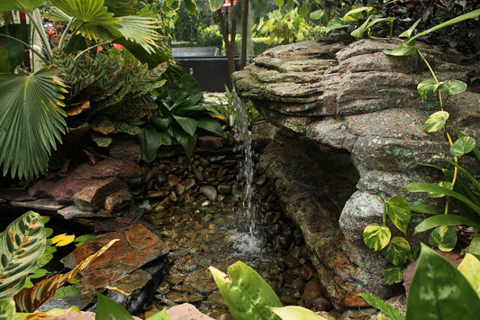 A small waterfall in a garden surrounded by greenery