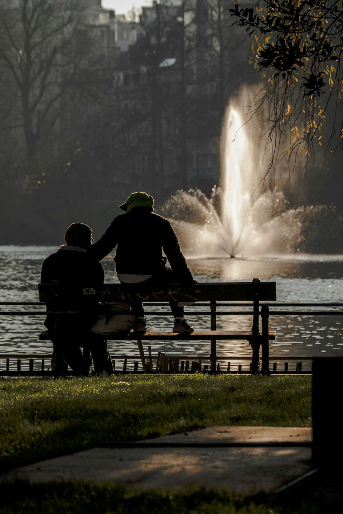 Two people sitting on a bench near a fountain