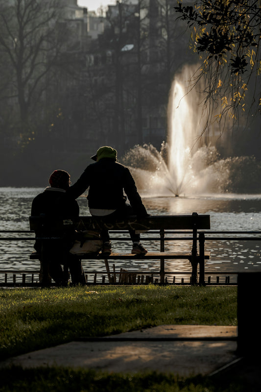Two people sitting on a bench near a fountain