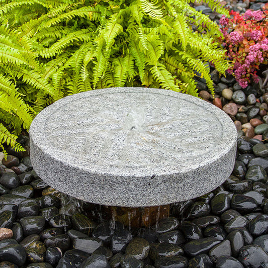 Angled view of a millstone style granite stone fountain