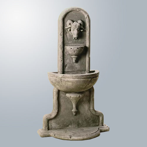 Outdoor water fountain with ram head design mounted on a wall