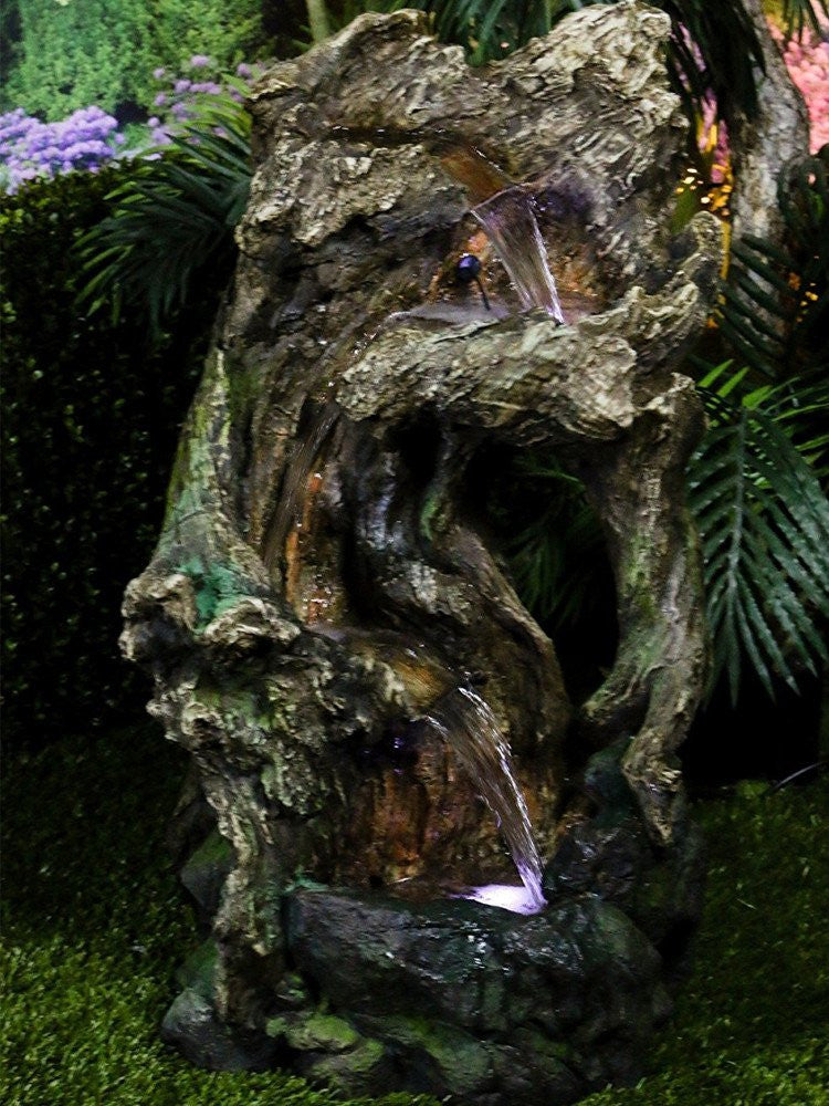 Outdoor water feature resembling a tree trunk with integrated LED lighting